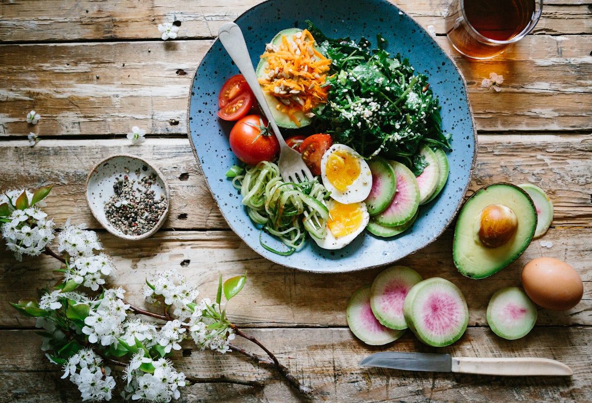A fresh, colorful salad bowl with vegetables and egg on a rustic wooden table